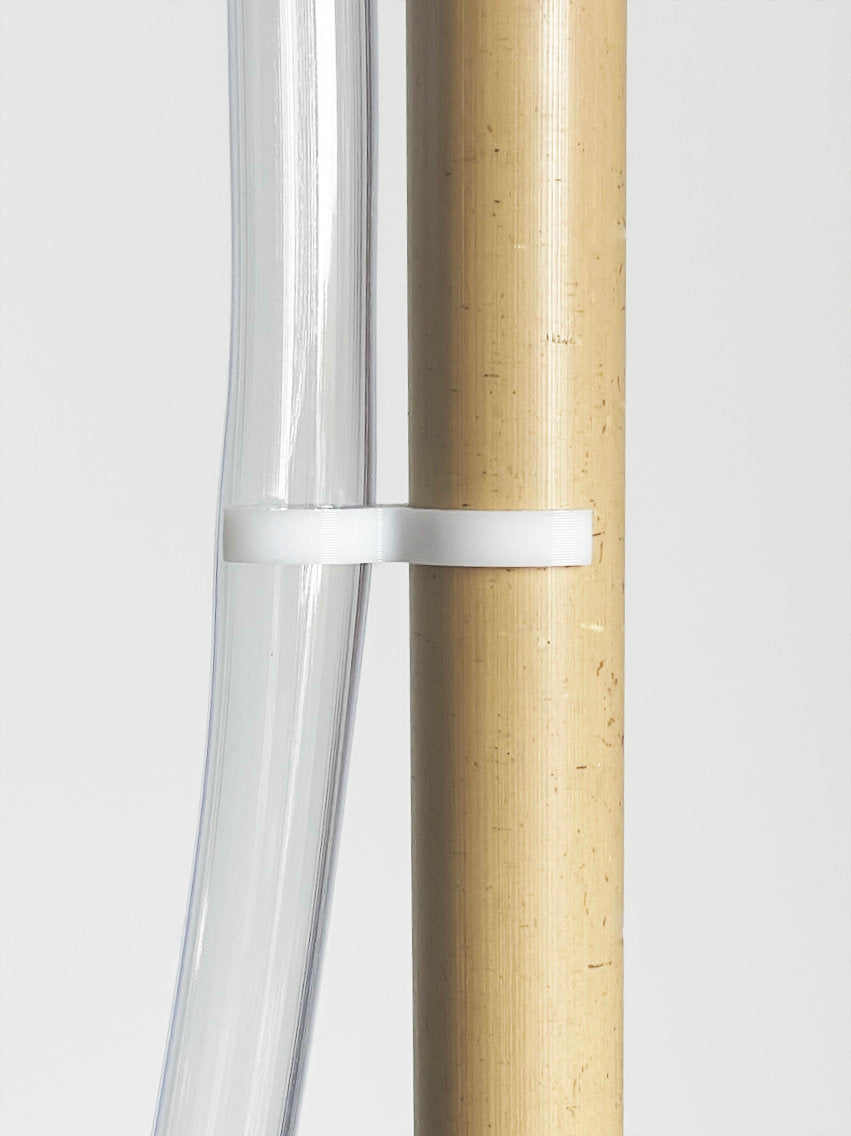 Produktfoto mit Schlauch, Bambus und weißer Halterung vor hellem Hintergrund.